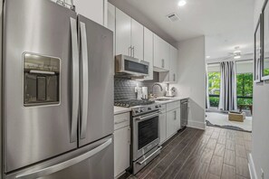 A modern kitchen with stainless steel appliances, a microwave, oven, and a built-in range hood. - Luxury Holiday Home Near Vandy 1 Mile to Music Row (Nashville)