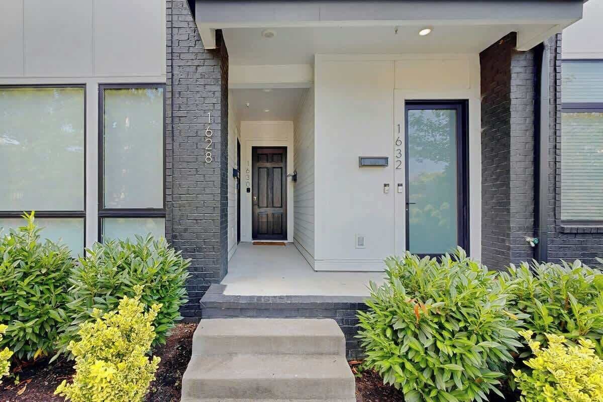 A modern building with a front entrance, a door with a number plaque, and a staircase leading to the entrance.