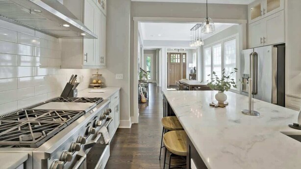 A modern kitchen with a central island, stainless steel appliances, and a view into the dining area. - Recently-built all-suite with two porches, firepit, crow's nest, & widow's walk (Franklin)