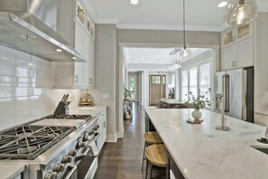 A modern kitchen with a central island, stainless steel appliances, and a view into the dining area.