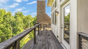 A wooden deck with a brick chimney, a glass door, and a view of trees. - Recently-built all-suite with two porches, firepit, crow's nest, & widow's walk (Franklin)