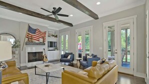 A spacious living room with a fireplace, sofas, a coffee table, and a ceiling fan. - Recently-built all-suite with two porches, firepit, crow's nest, & widow's walk (Franklin)