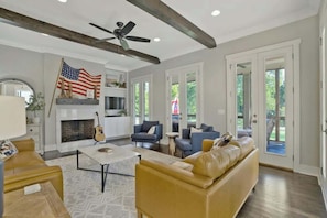 A spacious living room with a fireplace, sofas, a coffee table, and a ceiling fan.