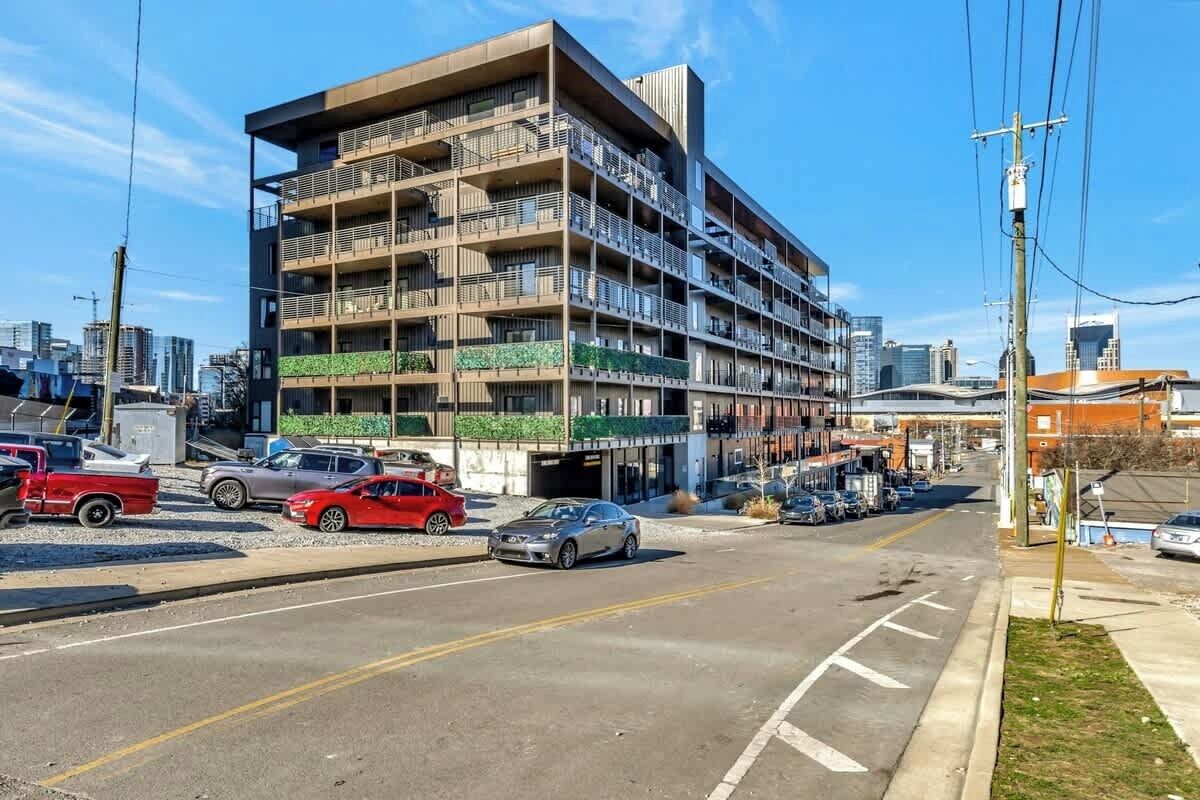 A multi-story building with balconies, a parking lot, and a clear sky.