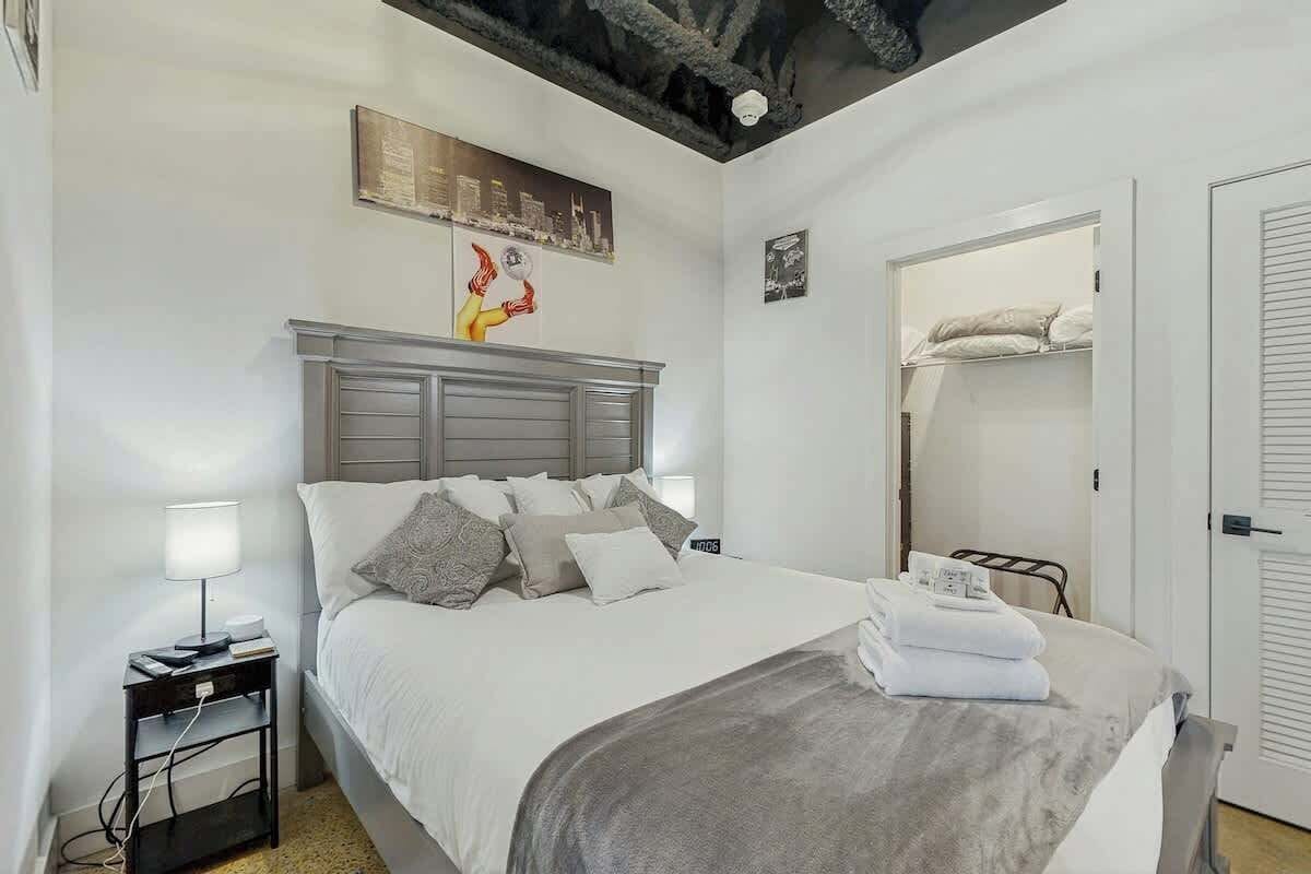 A bedroom with a bed, bedside tables, a wardrobe, and a ceiling with a unique design.