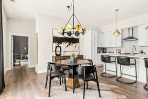 A modern kitchen with white cabinets, a central island, and bar stools. - Spacious Modern Condo, Near Vanderbilt & Broadway (Nashville)