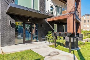 A modern building with a glass door entrance, a visible number '119', and outdoor seating. - Spacious Modern Condo, Near Vanderbilt & Broadway (Nashville)