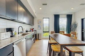 Eine moderne Küche mit Essbereich, großen Fenstern und Blick auf die Stadt.