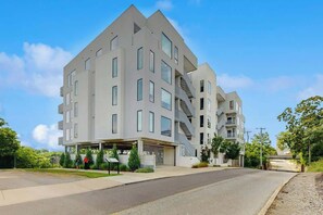 Un edificio residenziale moderno a più piani con garage, una scala e un'area di parcheggio coperta.