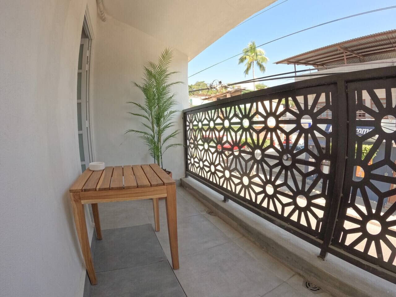 Un balcon avec une table en bois, une balustrade en métal décorative et une vue sur la rue.