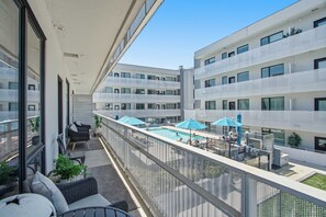A balcony with outdoor seating, a swimming pool, and a view of adjacent buildings. - Pool View Balcony, Near Attractions, Grill, Gym (Nashville)