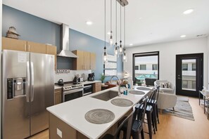 A modern kitchen with stainless steel appliances, a central island, and a dining area with a view of the city. - Pool View Balcony, Near Attractions, Grill, Gym (Nashville)