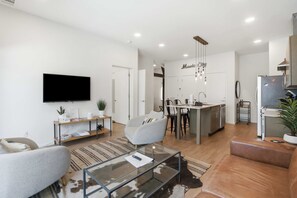 A modern living room with a flat-screen TV, a glass coffee table, and a sofa. - Pool View Balcony, Near Attractions, Grill, Gym (Nashville)