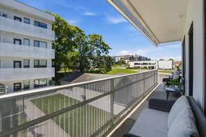A balcony with a mesh railing, a sofa, and a small table with chairs. - Pool View Balcony, Near Attractions, Grill, Gym (Nashville)