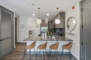 A modern kitchen with a central island, bar stools, and a large mirror. - 1.2 Mi to DT Nashville・City View Condo W Rooftop (Nashville)
