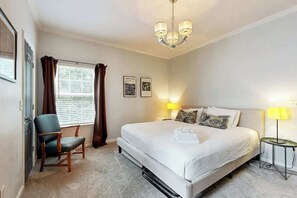 A hotel room with a bed, a chair, a lamp, and a window with curtains.