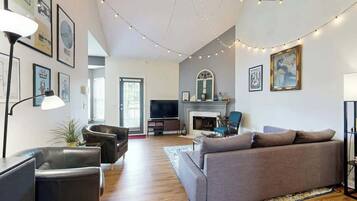 A living room with a sofa, chairs, a TV, a fireplace, and string lights.