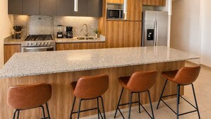 Eine moderne Küche mit Granit Arbeitsplatte, Edelstahlgeräten und Holzschränken.
