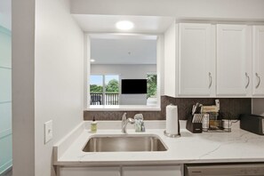 A modern kitchen with a built-in sink, white cabinets, and a window overlooking a balcony. - Nashville Riverfront Retreat Near Broadway Pool (Nashville)