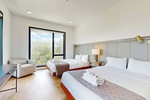 A hotel room with two beds, a desk, a chair, a nightstand, and a large window. - Penthouse condo with WiFi, balcony, seasonal courtyard pool, & fitness center (Nashville)
