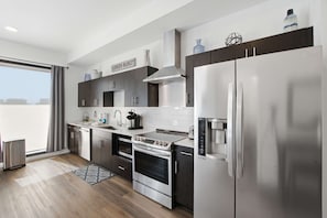 A modern kitchen with stainless steel appliances, a built-in oven, and a large refrigerator. - Luxe Top Floor Condo, Courtyard Pool, Gym Access (Nashville)