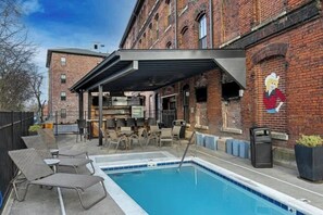 A pool area with lounge chairs, a covered seating area, and a brick building with a mural. - Midtown Nashville Penthouse・Dog OK・Pool・Rooftop (Nashville)