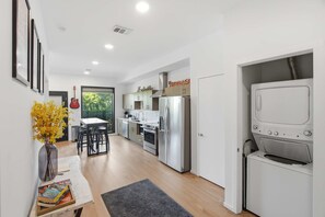 A modern kitchen with stainless steel appliances, a dining area with a table and chairs, and a laundry room with a washing machine. - Skyline-View Condo with Seasonal Pool Gym Access (Nashville)