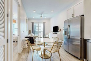 A modern kitchen with a large stainless steel refrigerator, a dining area with a round table and chairs, and a living area with a sofa and TV. - Stylish condo with balcony, high speed internet, WD and elevator (Nashville)