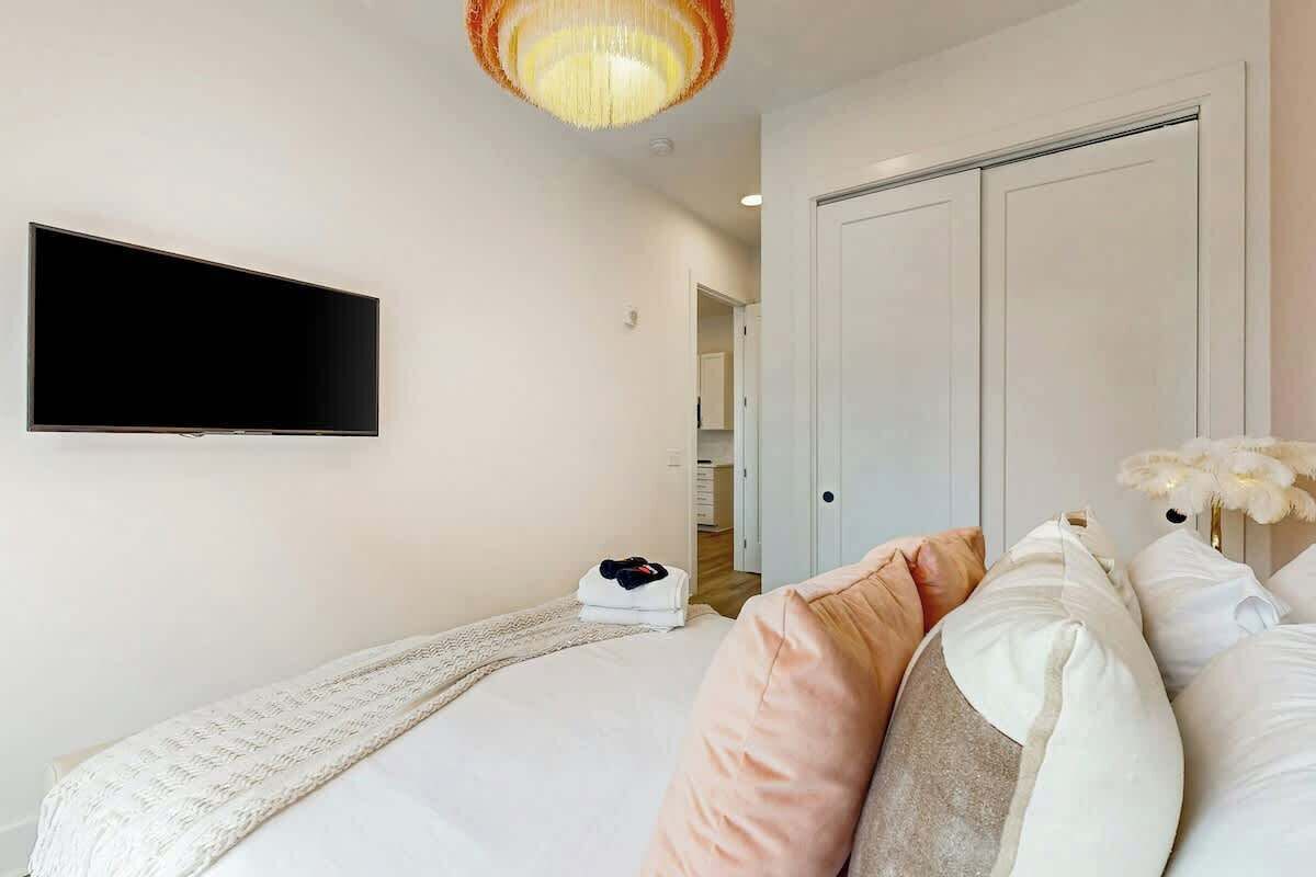 Une chambre à coucher comprenant un lit, un téléviseur à écran plat, une armoire et une porte donnant sur une salle de bain.