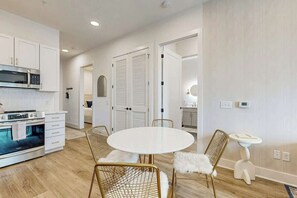 A modern kitchen with white cabinetry, a built-in oven, and a dining area with a round table and wire-framed chairs. - Stylish condo with balcony, high speed internet, WD and elevator (Nashville)