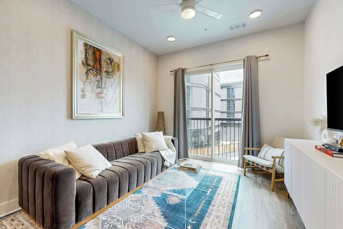 Una sala de estar moderna con un sofá, una mesa de centro, un televisor y un balcón con vistas.