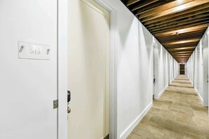 A long, narrow hallway with white walls and a wooden ceiling. - Modern Midtown loft with all-new interior & amazing park views - near Vanderbilt (Nashville)