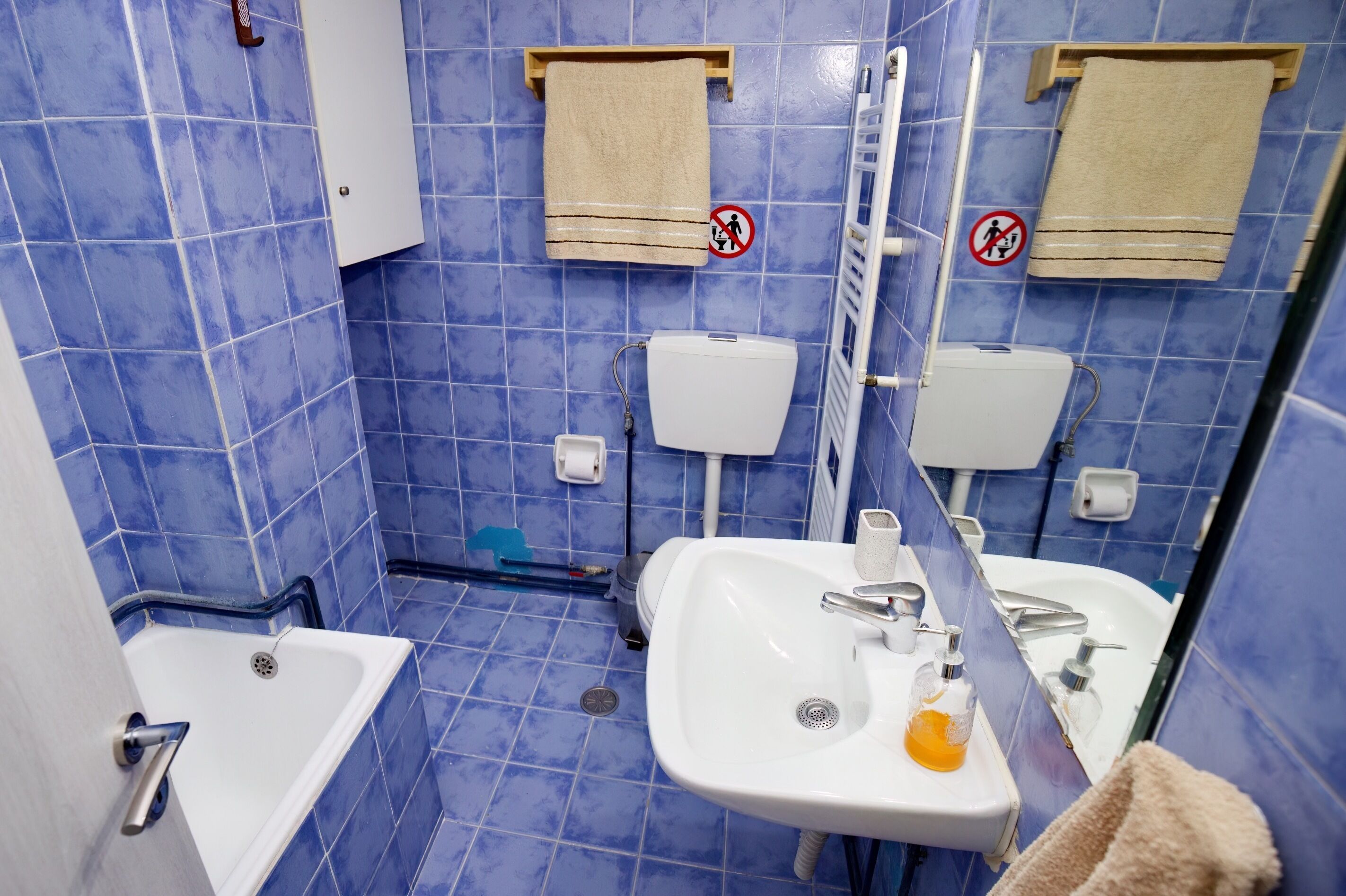 Een badkamer met blauwe tegels, een wit wastafel, toilet en bad.