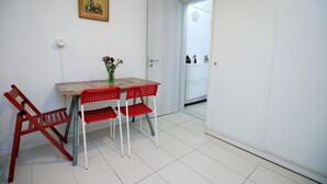 Ett rum med en vit dörr, ett bord med en blomvas och röda stolar.
