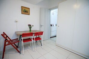 A room with a white door, a table with a floral vase, and red chairs. - Under Lycabettus Hideaway by ΜΡS (Athina)