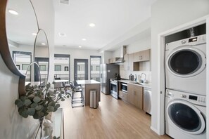 A modern kitchen with stainless steel appliances, a built-in oven, and a washing machine. - Poolside Balcony, Near Downtown, In-unit Laundry (Nashville)