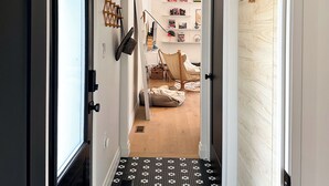 Un couloir avec un sol à motifs noir et blanc, un plafond blanc et une porte en bois sur le côté droit.