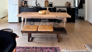 Une cuisine moderne avec une table en bois, un réfrigérateur blanc et un luminaire suspendu.