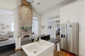 A modern kitchen with a brick wall, stainless steel appliances, and a black countertop. - 1920s Dog  Welcome Escape N East Nashville, Firepit (Nashville)