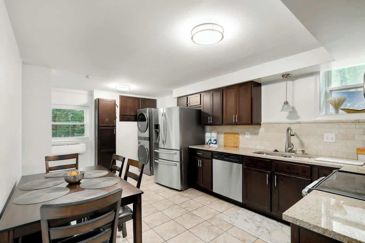 A modern kitchen with a dining area, stainless steel appliances, and a window with a view.