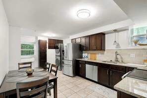 A modern kitchen with a dining area, stainless steel appliances, and a window with a view. - Cumberland River Retreat Near Downtown Airport (Nashville)