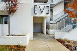A modern building entrance with a prominent sign, a staircase, and a tree. - Luxe 5th Floor Downtown Condo, Riverfront W Views (Nashville)