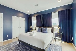 A modern hotel room with a large bed, a nightstand, a window with curtains, and a view of the city. - Luxe 5th Floor Downtown Condo, Riverfront W Views (Nashville)