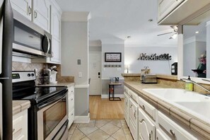 A modern kitchen with white cabinetry, a built-in microwave, and a large sink. - Renovated Downtown Nashville Apartment + Elevator (Nashville)