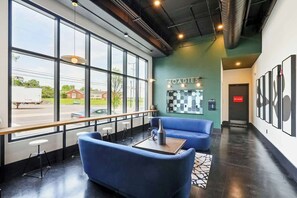 A modern interior with large windows, a checkered wall art, and a blue seating area. - Muse | Classy downtown condo with AC, rooftop lounge & fitness room (Nashville)