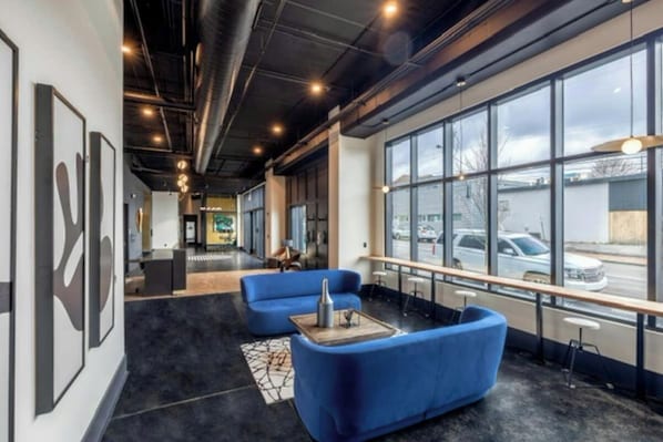 A modern interior with a seating area, large windows, and artwork on the walls. - Muse | Modern condo in great downtown location with balcony & rooftop lounge (Nashville)