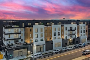 A modern multi-story building with balconies, a parking area, and a street view. - Muse | Modern condo in great downtown location with balcony & rooftop lounge (Nashville)