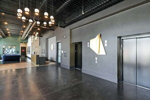 A spacious lobby with a modern design, featuring a large reception desk, a seating area, and a wall-mounted artwork. - Muse | Modern condo in great downtown location with balcony & rooftop lounge (Nashville)