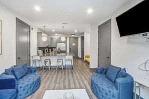 A modern living room with a central island, two sofas, and a flat-screen TV mounted on the wall. - City Views・2BR Private Balcony・Downtown Location (Nashville)