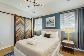 A bedroom with a bed, bedside tables, a chandelier, a painting, and a window with curtains. - 0.2 Mi 12 South・Modern Nashville Getaway, Sleeps 2 (Nashville)